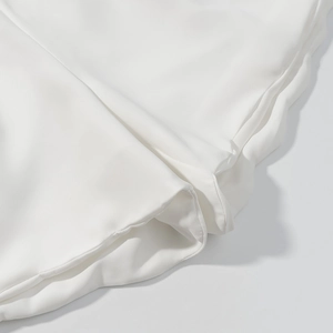 Gros plan sur les coutures soignées et la texture douce de cet ensemble blanc deux pièces