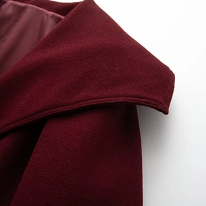 Detailed close-up of stitching and wool blend texture on a burgundy jacket collar