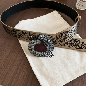 Detail of vintage heart-shaped belt buckle with rose relief and black floral print strap
