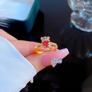 Close-up of gold-plated bear ring featuring a red heart gemstone and white zircons