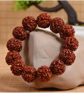 Detailed macro shot of deep reddish-brown Rudraksha beads on smooth river stones