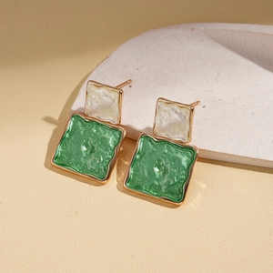 Macro detail of retro geometric square earrings with vintage green enamel and gold texture