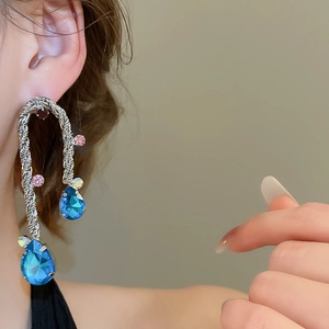 Dettaglio orecchini a goccia argento con pietre blu e metallo intrecciato sulla modella