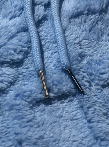 Dettaglio macro del tessuto in pile azzurro e coulisse con punta in metallo pregiato