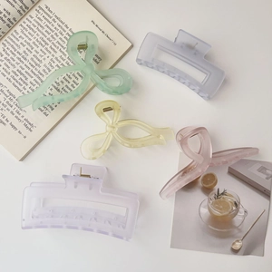 Flat lay of colorful acrylic hair claws in green, pink, and blue on a minimalist background