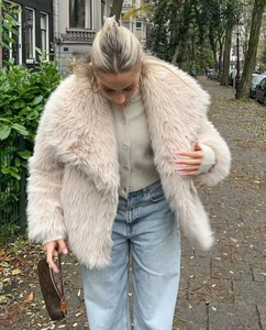 Dettaglio cappotto di pelliccia sintetica beige con texture morbida e collo a rever