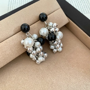 Detail of beaded cluster earrings with black beads and faux pearls in a velvet jewelry box