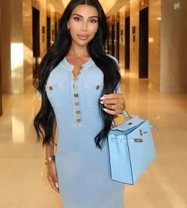Detail of light blue knit dress featuring gold buttons and fringed neckline collar