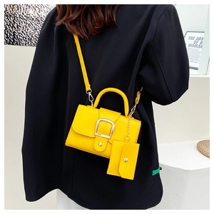 Detail view of yellow crossbody bag with silver buckle and matching small coin purse