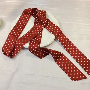 Detail of a red polka dot silk scarf draped on a vintage white embossed ceramic plate