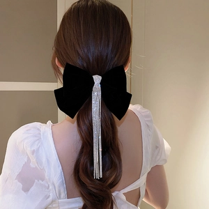 Detail of elegant black velvet bow hair clip with sparkling rhinestone fringe tassels