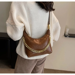 Detail of brown quilted leather bucket bag with chunky gold chain strap on model