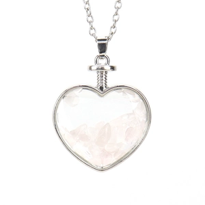 Macro shot of heart-shaped pendant filled with natural pink rose quartz stone chips