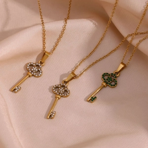 Detail view of gold key pendants with white zircons, pearls and green gems on silk