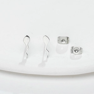 Minimalist silver tadpole stud earrings with polished finish on a white display plate