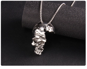 Détail macro du pendentif demi-crâne gothique argenté avec chaîne box en acier