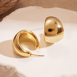 Close-up of chunky gold-plated C-shaped earrings with a high-polished mirror finish