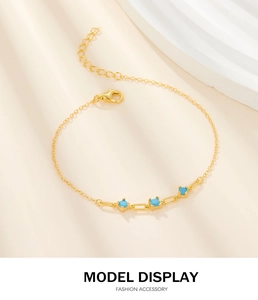 Detail of gold chain bracelet featuring square blue turquoise stones and lobster clasp