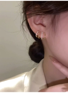 Detail of four-row gold crawler earrings with white zircon stones on model ear