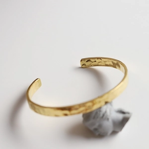 Detailed view of gold plated titanium steel bangle with irregular hammered texture