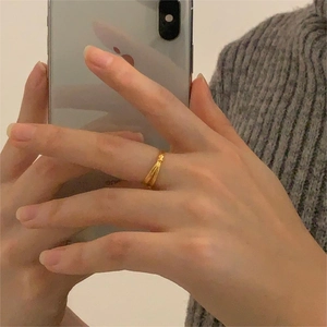 Close-up of golden multi-layer intertwined ring worn on index finger in casual setting