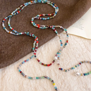 Bohemian crystal beaded necklace with white pearls on a soft textured background