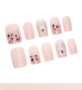 Close-up of pink press-on nails with silver butterflies and sparkling glitter accents
