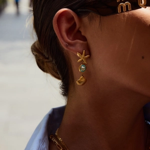 Detail of gold starfish earring with turquoise bead and shell on ear model