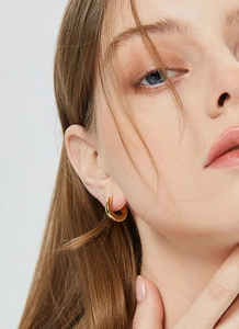 Macro view of minimalist C-shape gold hoop earring on model showing polished metal texture