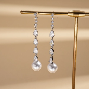Elegant silver tassel earrings with teardrop zircons and white pearls on a gold stand