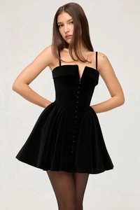 Detail shot of black velvet dress showing deep V-neck, collar, and delicate cloth buttons