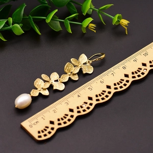 Elegant gold floral drop earrings with white teardrop pearls and 6.5cm scale display