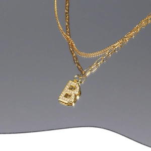 Detail of gold layered necklace with paperclip chain and zircon-studded letter B charm