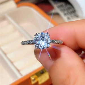 Detailed close-up of a four-prong set solitaire ring with a pavé band in a gift box