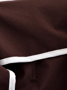 Dettaglio dei pantaloni vintage marrone scuro con bordino bianco e trama in twill