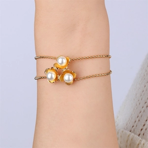 Detail of 18k gold plated double-layer bracelet with shell flowers and white pearls