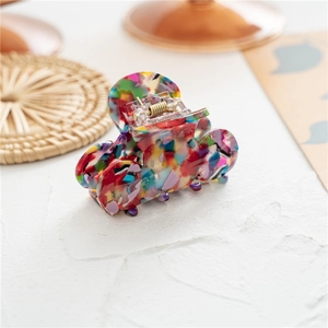Close-up of a colorful mosaic pattern acetate hair claw clip with a gold metal spring