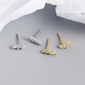 Macro shot of silver and gold marquise zircon stud earrings on minimalist paper background