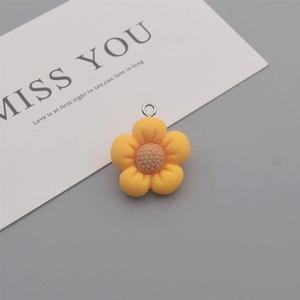 Macro detail of yellow resin five-petal flower pendant with silver metal jump ring