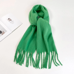 Flat lay macro detail of bright green mohair scarf featuring long fringe and soft texture