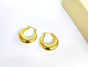 Detail of 18K gold crescent hoop earrings with a thick hollow design on white background