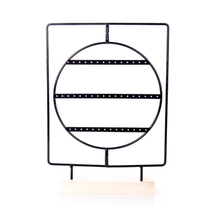 Detail of black metal earring display stand with three-row holes and solid wooden base
