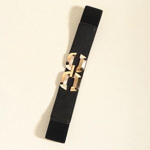 Close-up of golden metal chain-link buckle and black textured leather on elastic belt