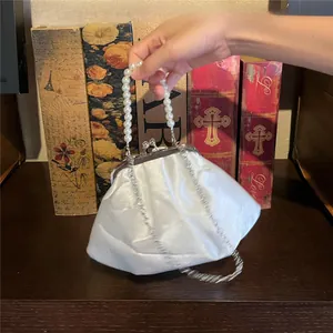 Detail of white satin cloud handbag with pearl handle and detachable silver chain
