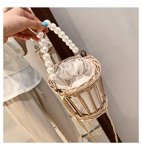 Close-up of woven bucket bag with pearl handle, drawstring pouch, and gold chain