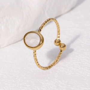Anello regolabile dorato con pietra bianca rotonda su una base in pietra testurizzata