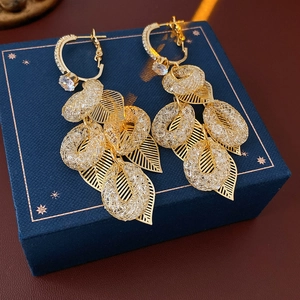Dettaglio orecchini a foglia d'oro con anelli ovali su scatola regalo blu scuro