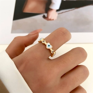 Detail of evil eye ring with white enamel hearts and cubic zirconia on gold band