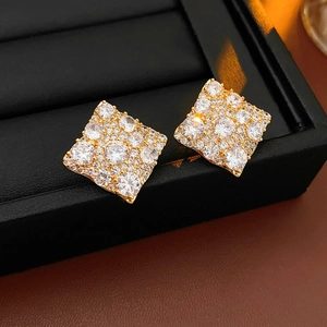 Gros plan de boucles d'oreilles carrées en zircon plaqué or sur un présentoir en cuir noir