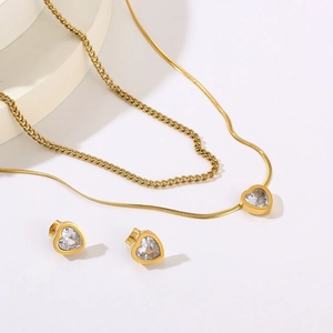 Detail of gold layered stainless steel necklace and heart earrings with clear stones